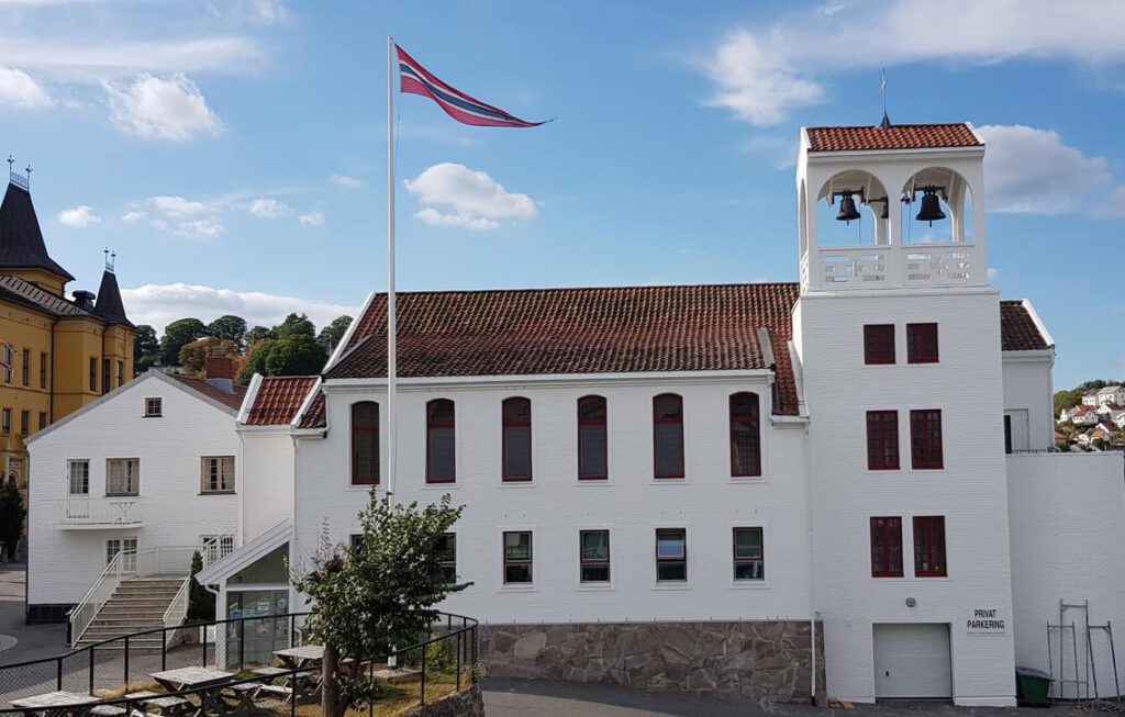 Avstands utsnitt av Kirken og prestegarden, en stor hvit kirke med rødt/brunt tak